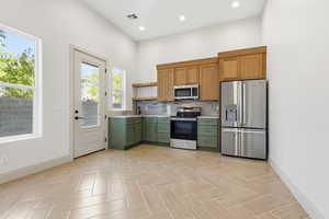 Kitchen with stainless steel appliances, green cabinetry, open shelves, backsplash, and recessed lighting
