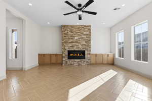 Unfurnished living room with a stone fireplace, a ceiling fan, and recessed lighting