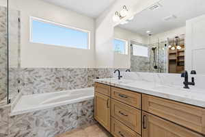 Bathroom featuring a spacious closet, double vanity, a bath, and a stall shower