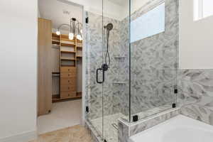 Full bath featuring light colored carpet, a shower stall, a bath, a spacious closet, and light tile patterned floors