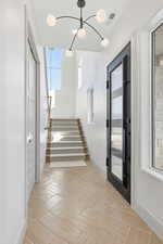 Staircase with baseboards and a chandelier