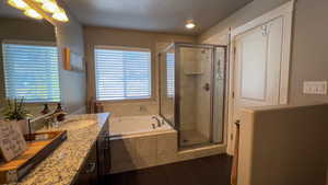 Bathroom featuring a garden tub, vanity, dark tile patterned flooring, and a shower stall