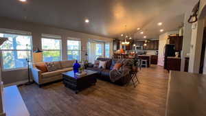 Living area featuring recessed lighting, lofted ceiling, a chandelier, and dark wood finished floors