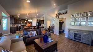 Living room featuring arched walkways, dark wood-style flooring, recessed lighting, a chandelier, and high vaulted ceiling