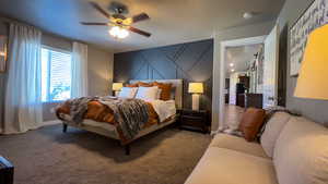 Carpeted bedroom with ceiling fan and an accent wall