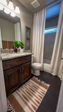 Full bathroom featuring dark tile patterned flooring, vanity, and shower / bath combo
