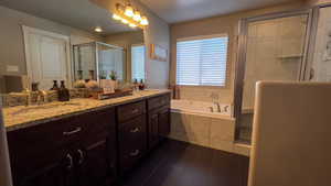 Full bathroom with a stall shower, a bath, double vanity, and dark tile patterned flooring