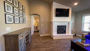 Living room featuring arched walkways, dark wood-type flooring, and a premium fireplace
