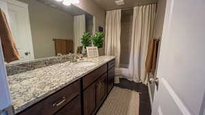 Bathroom with vanity, dark tile patterned floors, and shower / bath combo with shower curtain