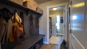 Mudroom featuring dark wood-type flooring and stacked washer / dryer