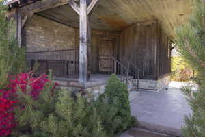 View of exterior entry with stone siding and a porch