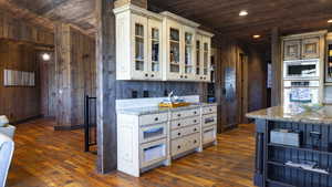 Kitchen with open shelves, glass insert cabinets, wood ceiling, wooden walls, and dark wood-style floors