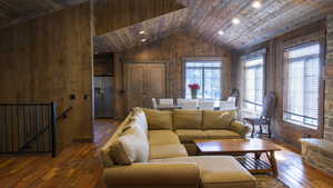 Living area with wood walls, hardwood / wood-style floors, wooden ceiling, and vaulted ceiling