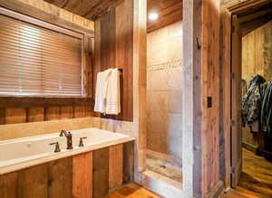 Full bath featuring a garden tub, a shower stall, wood walls, wood finished floors, and wooden ceiling