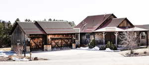 View of front of property featuring an attached garage, covered porch, stone siding, and driveway