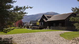 Rear view of property with stone siding, a yard, a deck with mountain view, a metal roof, and board and batten siding