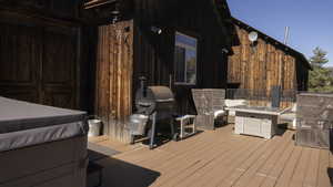 Wooden deck with a fire pit, grilling area, and a hot tub