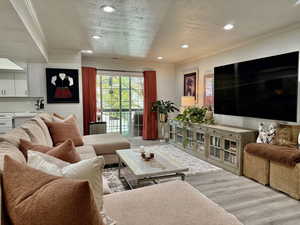 Living area featuring ornamental molding, recessed lighting, light wood finished floors, and a textured ceiling