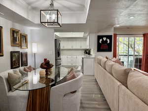 Dining area with ornamental molding, a raised ceiling, light wood finished floors, a textured ceiling, and a chandelier