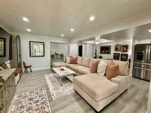 Living room with recessed lighting, light wood-style flooring, and crown molding