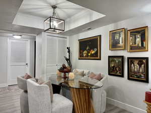 Dining room featuring light wood finished floors, ornamental molding, a chandelier, a tray ceiling, and a textured ceiling