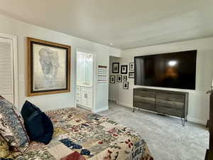 Carpeted bedroom with ensuite bathroom and baseboards