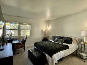 Bedroom featuring light carpet and an office area