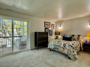 Bedroom with a textured ceiling, carpet floors, and access to exterior