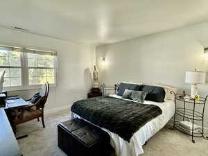 Bedroom featuring light colored carpet and an office area