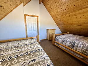 Bedroom with wooden ceiling, carpet flooring, and vaulted ceiling