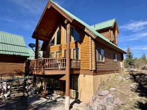 View of side of home featuring a metal roof, a deck, a patio, stairs, and log exterior