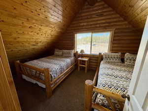 Carpeted bedroom featuring rustic walls, wooden ceiling, and vaulted ceiling