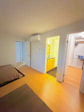 Unfurnished bedroom with light wood-type flooring and an AC wall unit