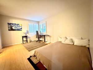 Bedroom with wood finished floors and an office area