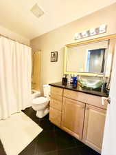 Full bathroom with dark tile patterned floors, vanity, and shower / bath combination with curtain