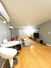 Living area with a wall mounted air conditioner and light wood-type flooring