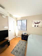 Bedroom featuring light wood finished floors and a wall mounted air conditioner