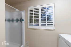 Bathroom featuring a shower stall, vanity, and washer / clothes dryer