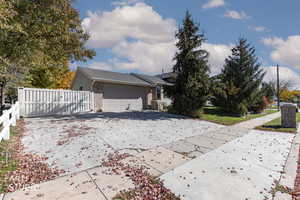 View of front of home with driveway, a garage, brick siding, and a gate