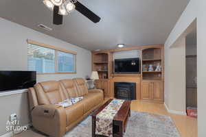 Living room with a wood stove, light wood-type flooring, and built in shelves
