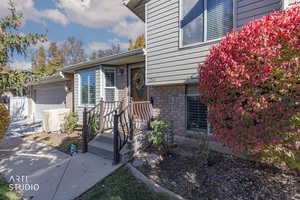 Doorway to property with brick siding, an attached garage, and driveway
