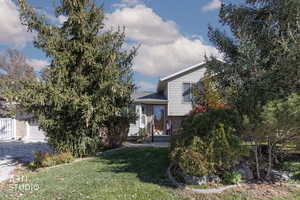 View of front facade with brick siding, a front yard, a garage, and driveway