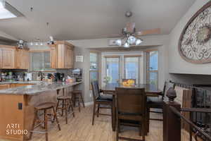 Dining area with light wood finished floors, a ceiling fan, and lofted ceiling