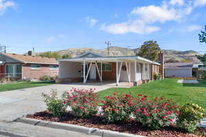 View of front of house featuring driveway, a porch, a carport, a front yard, and a mountain view
