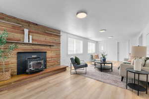 Living area with a wood stove, a textured ceiling, and wood finished floors
