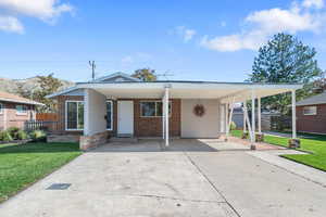 View of front facade with concrete driveway, an attached carport, and covered porch