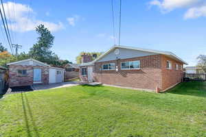 Back of property featuring a fenced backyard, an outbuilding, brick siding, a patio area, and a chimney