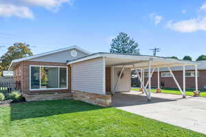 View of front facade with concrete driveway, an attached carport, and brick siding