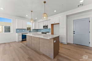Kitchen with backsplash, white cabinets, a kitchen island, light wood-type flooring, and recessed lighting