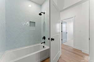 Bathroom with bathing tub / shower combination and light wood-style flooring